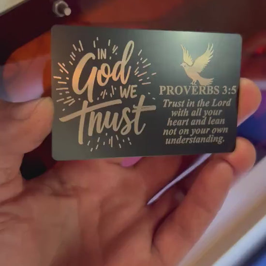 Hand holding In God We Trust laser engraved keepsake gift card with bible verse and dove typographic design