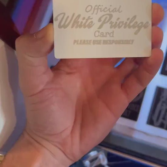 Close-up video of white/silver anodized metal card rotating to show laser engraved Official White Privilege card text