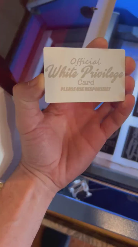 Close-up video of white/silver anodized metal card rotating to show laser engraved Official White Privilege card text