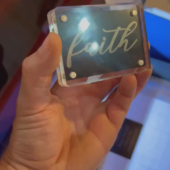 Hand holding a laser engraved metal keepsake card with cursive "Faith" typography, minimal faith inspired Christian gift