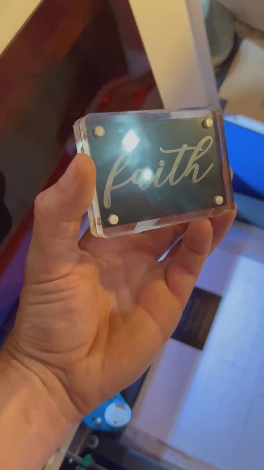 Hand holding a laser engraved metal keepsake card with cursive "Faith" typography, minimal faith inspired Christian gift