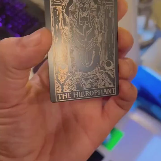 Video of a Hand holding a laser engraved Hierophant metal tarot card rotating under light to show reflective property