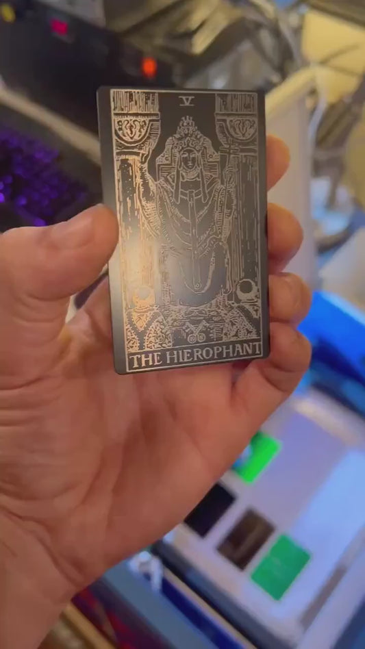 Video of a Hand holding a laser engraved Hierophant metal tarot card rotating under light to show reflective property