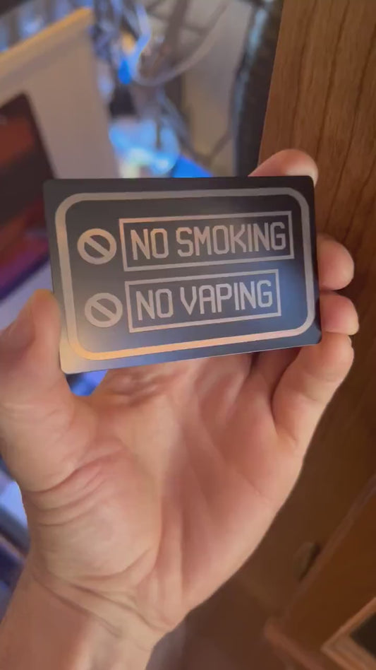Close up video of hand holding a laser engraved metal placard with No Smoking, No Vaping graphic