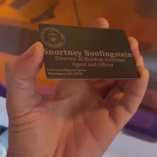 Close up video of hand holding a laser engraved metal business card with secret agent deputy director of the CIA design/layout