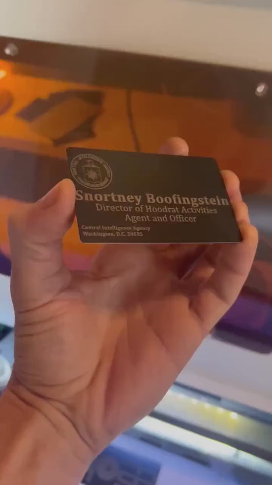 Close up video of hand holding a laser engraved metal business card with secret agent deputy director of the CIA design/layout