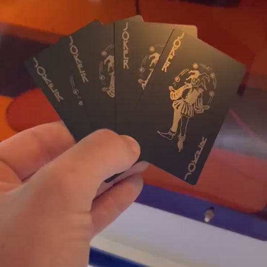 Close up video of hand holding 4 laser engraved metal playing cards with Joker juggling graphic and Joker Text