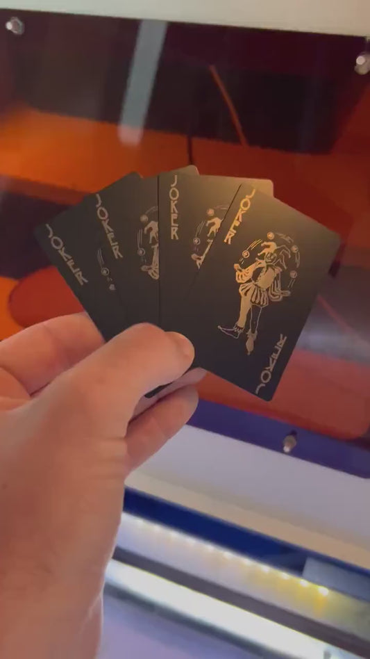 Close up video of hand holding 4 laser engraved metal playing cards with Joker juggling graphic and Joker Text