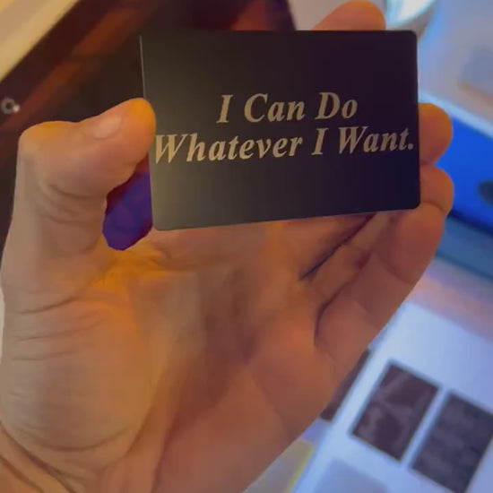 Hand holding a laser engraved black/silver metal I Can Do Whatever I Want text typography funny gag gift card