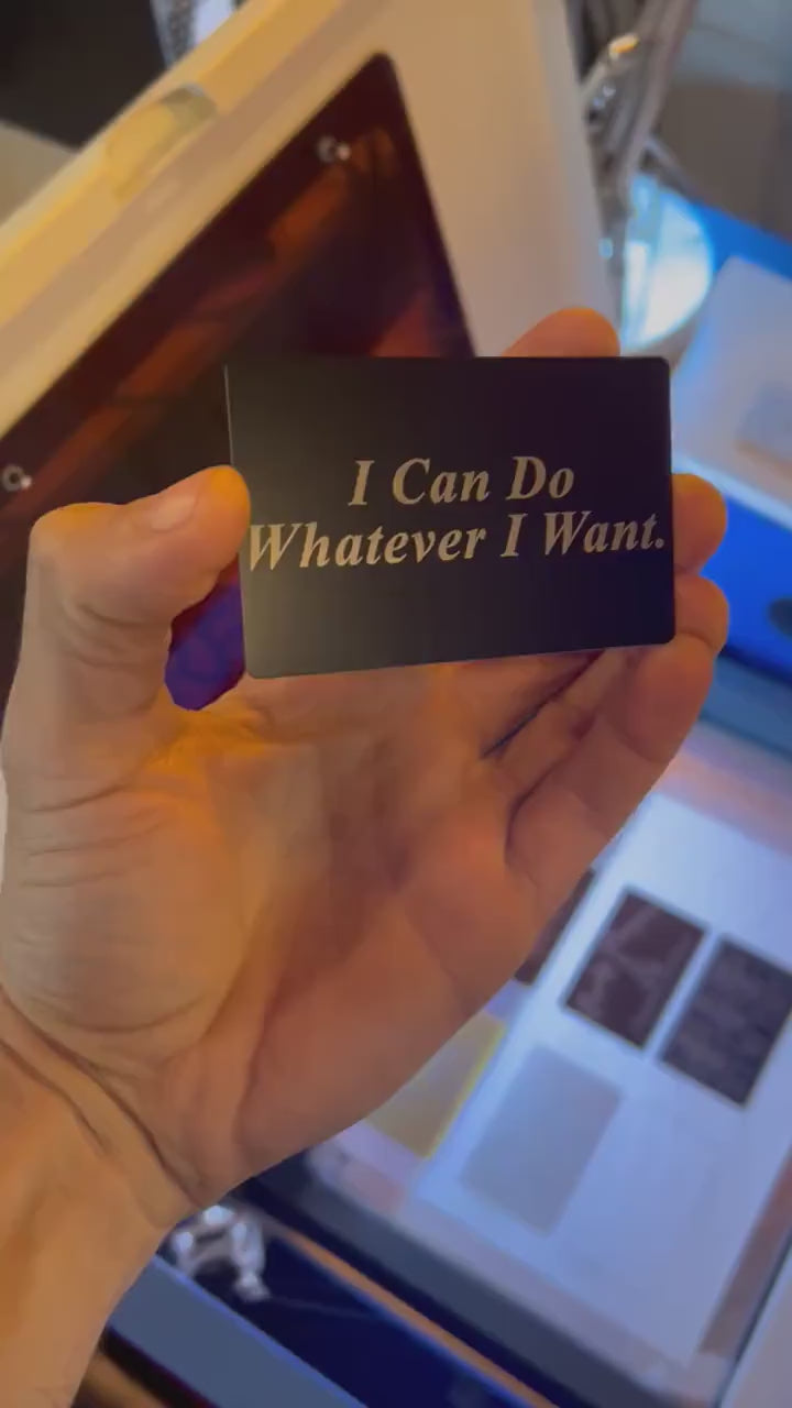 Hand holding a laser engraved black/silver metal I Can Do Whatever I Want text typography funny gag gift card