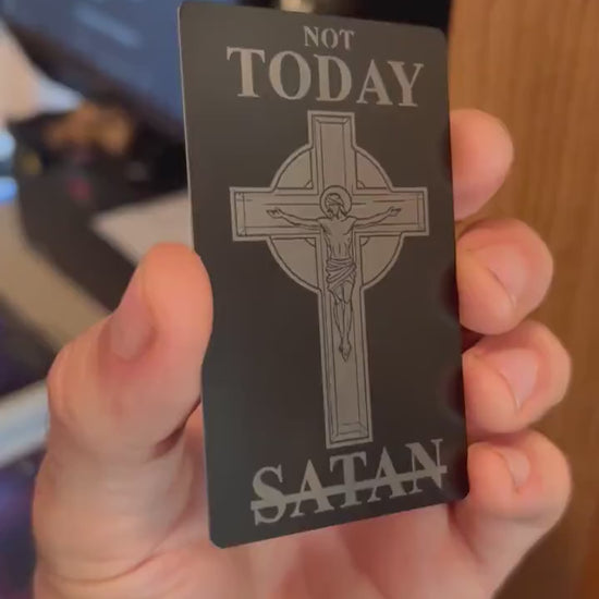 Engraved metal business card turning under light to highlight crucifix design and typography