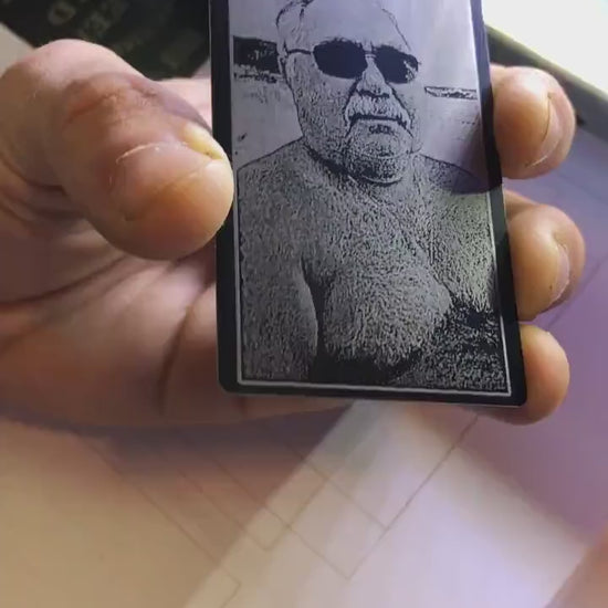 Close up video of hand holding a laser engraved metal photo portrait keepsake card with a picture of someone's father