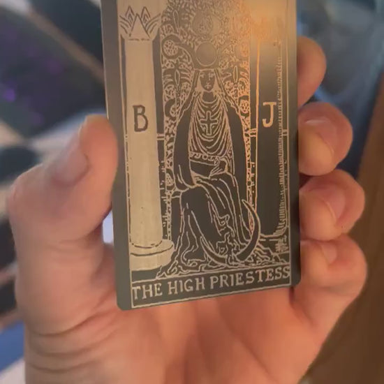 Close-up video of black anodized metal card rotating to show laser engraved high priestess tarot card
