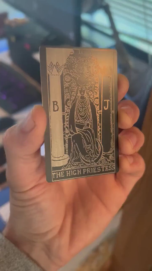 Close-up video of black anodized metal card rotating to show laser engraved high priestess tarot card
