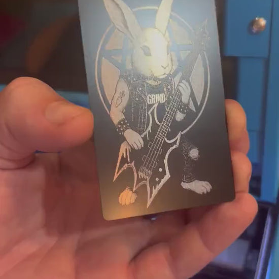 Hand holding a laser engraved metal keepsake card with heavy metal rocker rabbit playing bass illustration gift