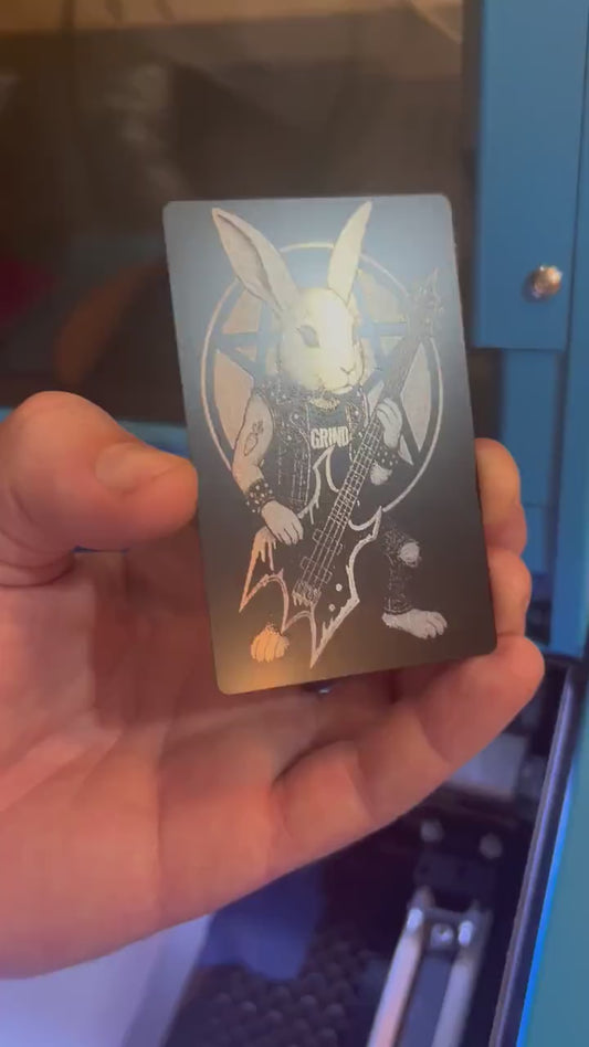 Hand holding a laser engraved metal keepsake card with heavy metal rocker rabbit playing bass illustration gift