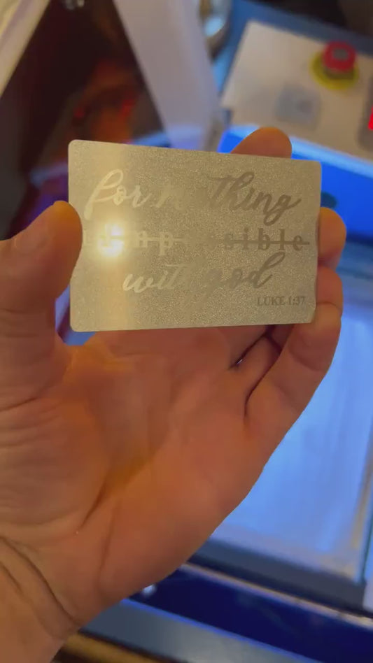 Video of engraved metal wallet card turning under light to show reflective finish with bible reference text