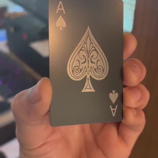 Close up video of hand holding a laser engraved metal gift card with Ace of Spades poker card design in matte black/silver