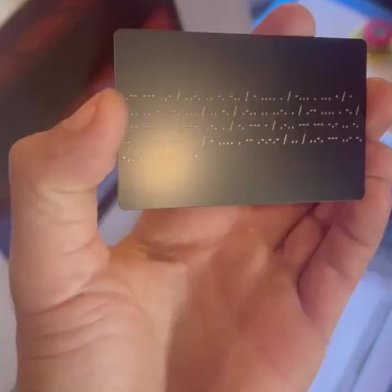 Hand holding metal laser engraved morse code card with personalized gift message translated into dots and slashes