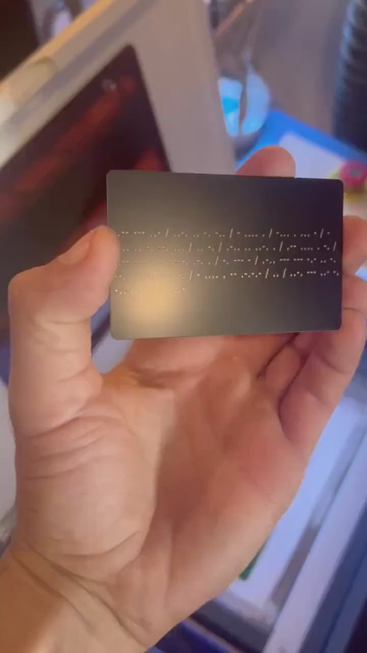 Hand holding metal laser engraved morse code card with personalized gift message translated into dots and slashes
