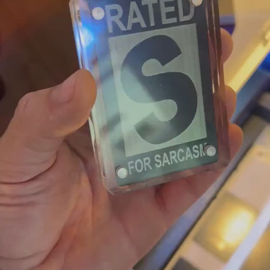 Hand holdling a Rated S for Sarcasm laser engraved keepsake gift card, shown in optional acrylic display case
