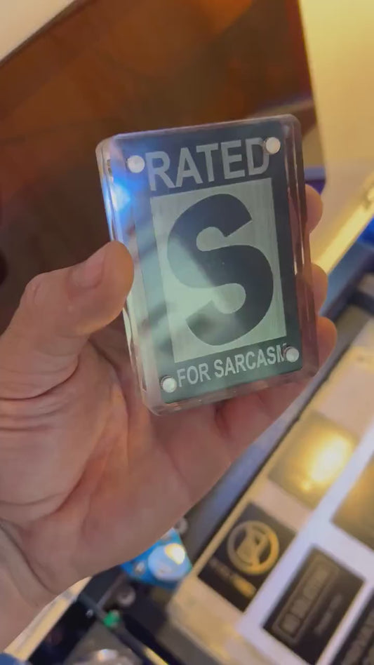 Hand holdling a Rated S for Sarcasm laser engraved keepsake gift card, shown in optional acrylic display case
