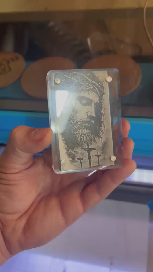 Close up video of hand holding a laser engraved metal keepsake gift card with Crown of Thorns Jesus Christ Crucifix illustration artwork engraving, shown in optional acrylic display case