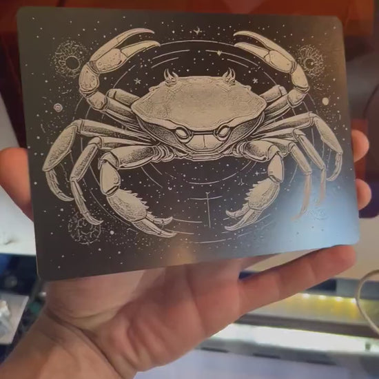 Hand holding laser engraved metal 5x7 plaque with cancer crab spiritual astrology zodiac artwork