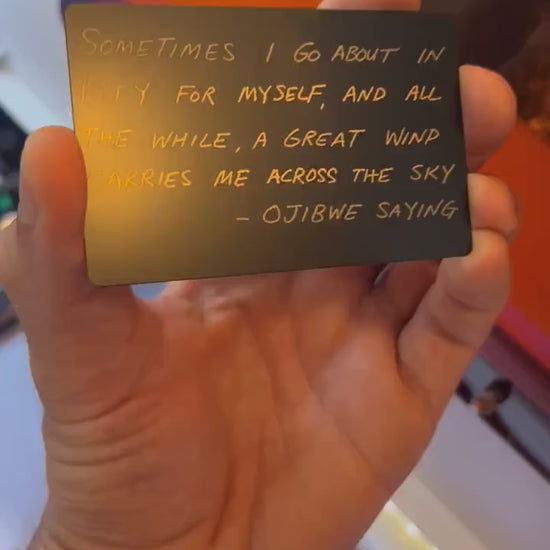 Hand holding laser engraved metal keepsake card with Sometimes I Go About in Pity For Myself card typography text