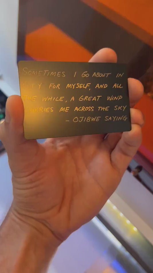 Hand holding laser engraved metal keepsake card with Sometimes I Go About in Pity For Myself card typography text
