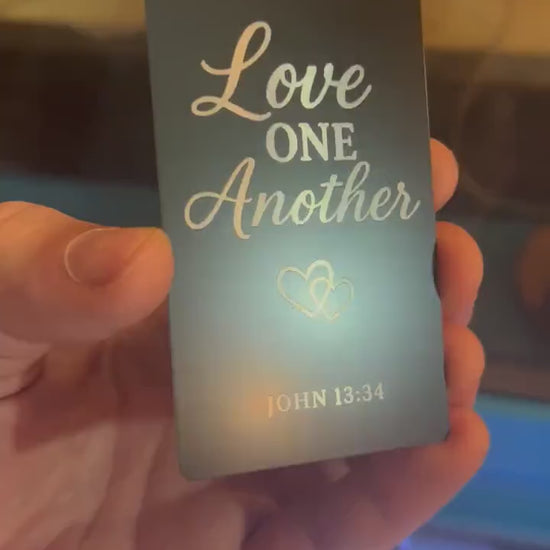 Close-up of engraved anodized aluminum scripture plaque featuring “Love One Another” message with Bible verse