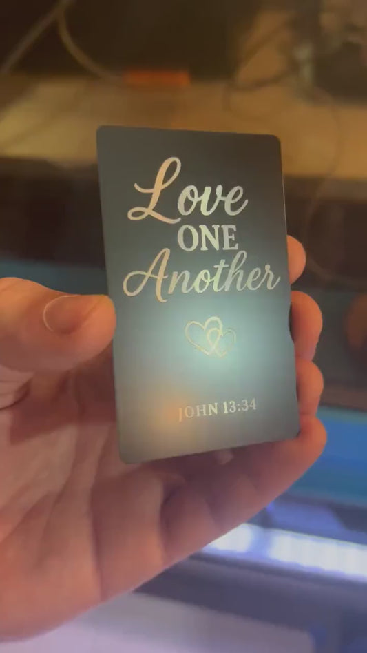 Close-up of engraved anodized aluminum scripture plaque featuring “Love One Another” message with Bible verse
