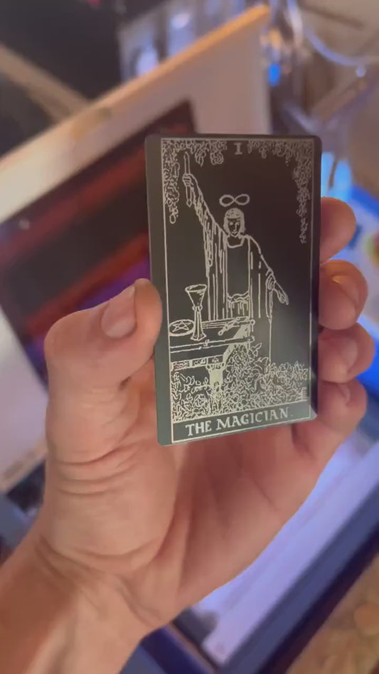 hand holding laser engraved The Magician metal tarot card in matte black/silver