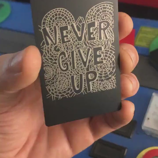 Laser engraved metal motivational reminder keepsake that reads Never Give Up with psychedelic pattern print