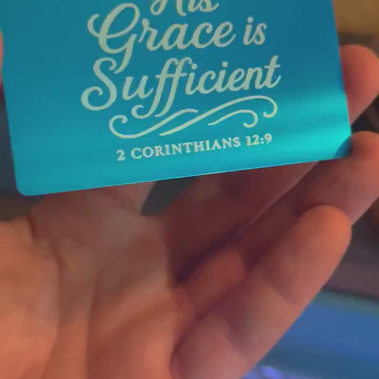 Hand holding a laser engraved metal wallet insert card that has inspirational Christian inspired typography and bible verse reference