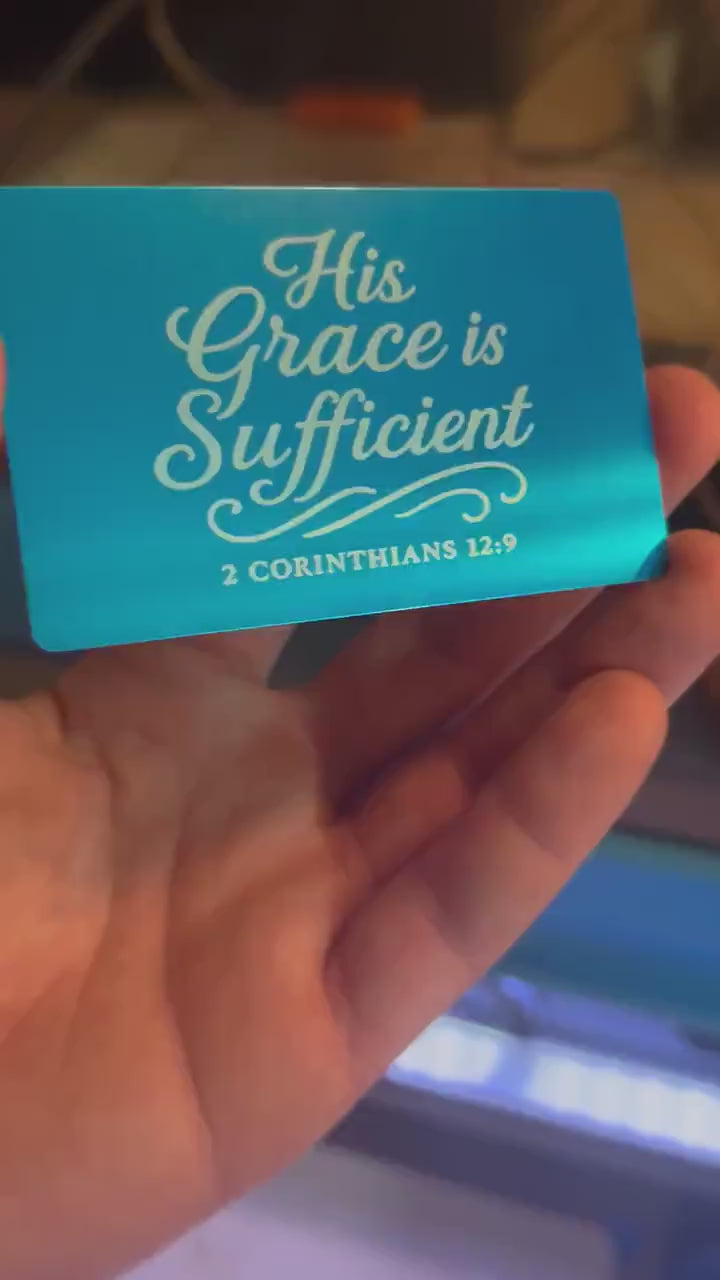 Hand holding a laser engraved metal wallet insert card that has inspirational Christian inspired typography and bible verse reference