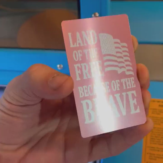 Close-up video of laser engraved metal land of the free home of the brave card rotating to show shine and detail