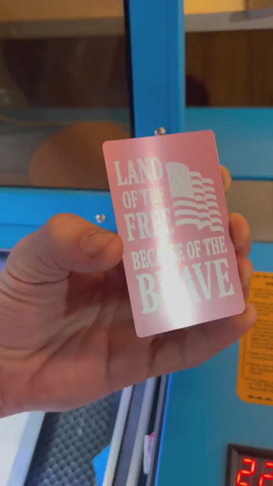 Close-up video of laser engraved metal land of the free home of the brave card rotating to show shine and detail