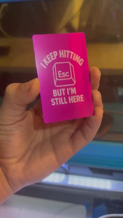 Hand holding a laser engraved purple and silver anodized aluminum I Keep Hitting Esc But I'm Still Here card