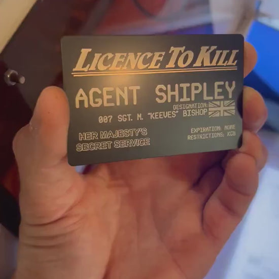 Hand holding a metal customized keepsake cosplay wallet card that reads License To Kill with custom name and text