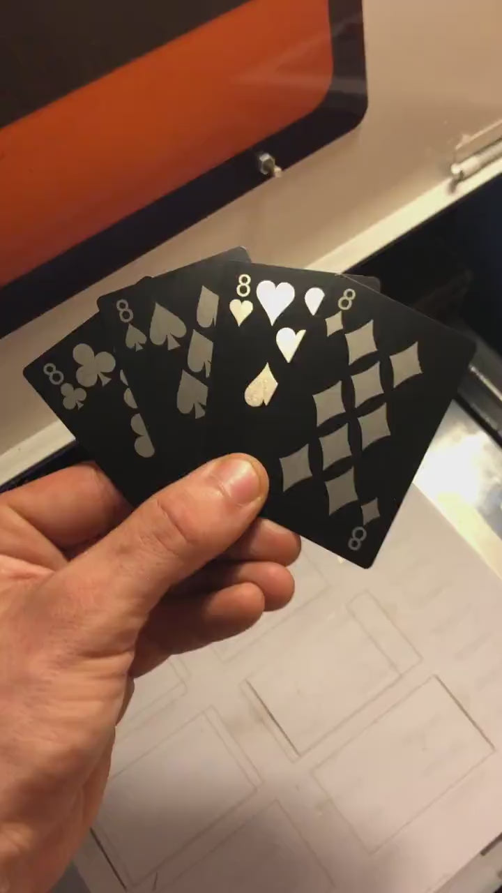 Close up video of hand holding 4 laser engraved metal poker cards with 9 of clubs, 8 of spades, eight of hearts, eight of diamonds cards