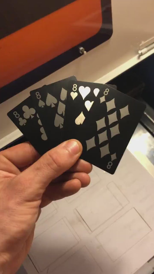 Close up video of hand holding 4 laser engraved metal poker cards with 9 of clubs, 8 of spades, eight of hearts, eight of diamonds cards