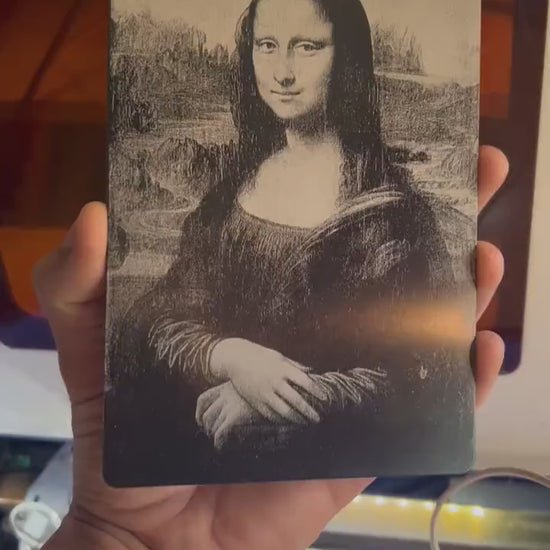 Hand holding a laser engraved 5x7 metal Mona Lisa plaque in anodized aluminum
