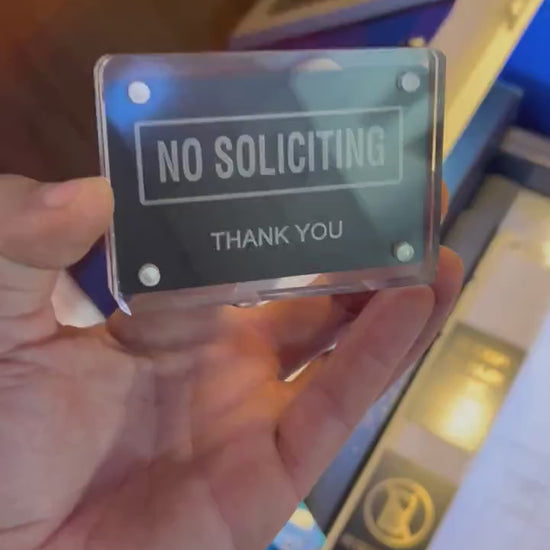 Detailed shot of engraved aluminum keepsake card with bold “No Soliciting” wording held in hand