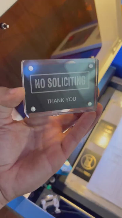 Detailed shot of engraved aluminum keepsake card with bold “No Soliciting” wording held in hand