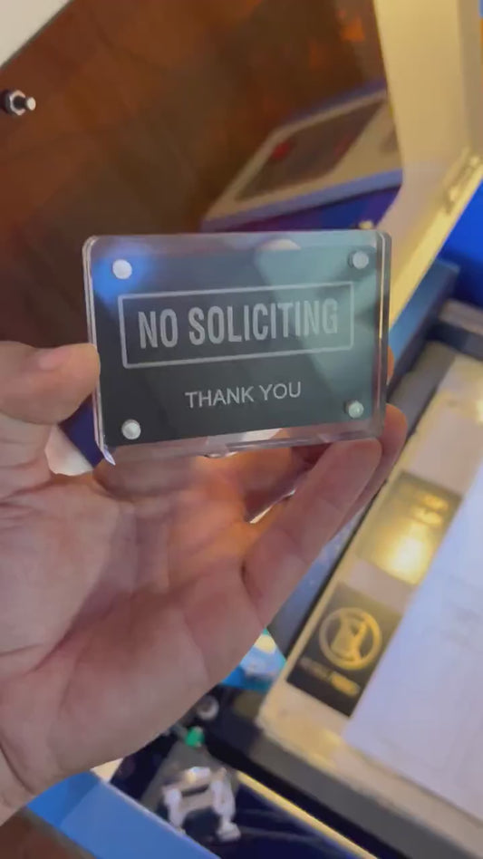 Detailed shot of engraved aluminum keepsake card with bold “No Soliciting” wording held in hand