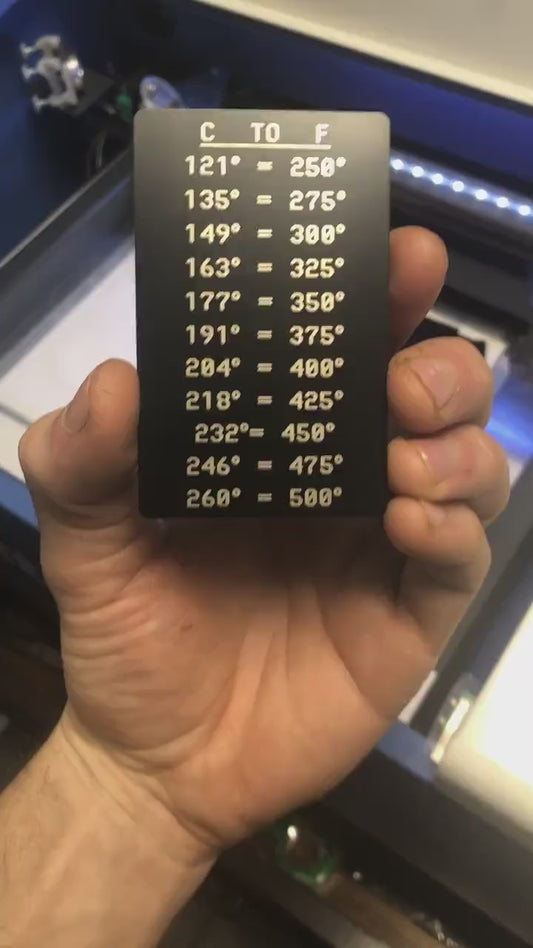 Hand holding a metal laser engraved baking conversion temperature chart with a set of Celsius and Fahrenheit temperatures