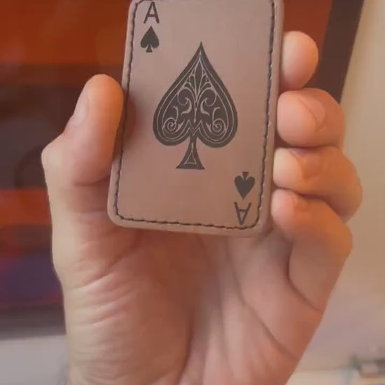 Hand holding a laser engraved brown leather ace of spades patch, rotating to demonstrate leather burning