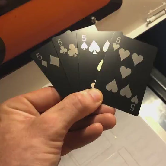 Hand holding a laser engraved black/silver metal playing cards Five of Diamonds, Five of Clubs, Five of Spades & Five of Hearts