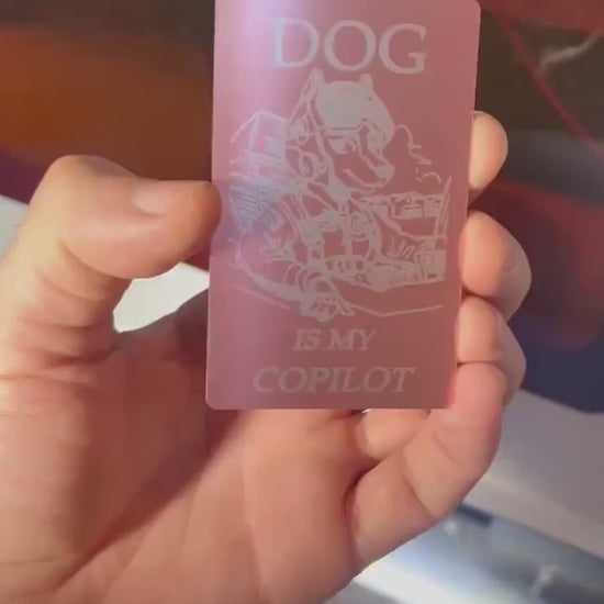 Close-up video of rose gold and silver anodized metal card rotating to show laser engraved dog is my co-pilot funny design and text